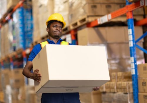 warehouse worker carrying lifting very heavy weight box moving storage box in cargo muscle back pain